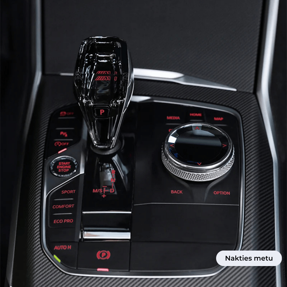 BMW automobilio interjeras su Crystal pavarų perjugimo svirtimi, sukamuoju valdymo ratuku ir įvairiais važiavimo režimo mygtukais vaizdas naktį.